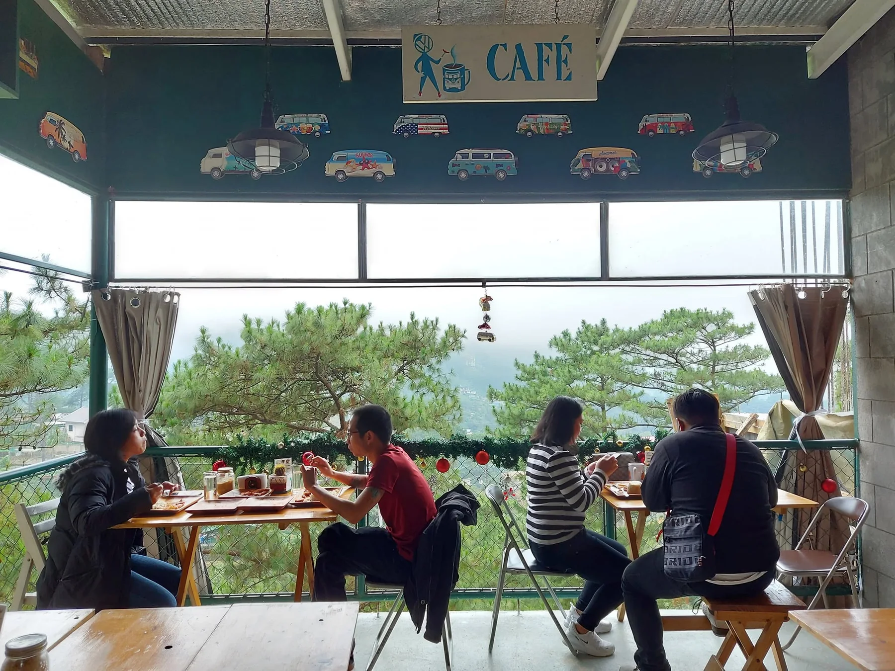 Campfolkswagen café guests beside an open view of Baguio pine trees